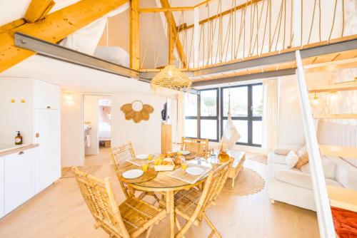 a dining room and living room with a table and chairs at Appart'Hôtel & Spa "Les Voiles" Le Molène in Carnac
