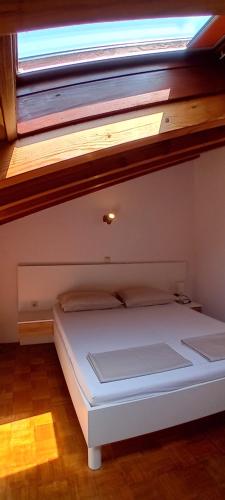 a small white bed in a room with a window at Jelena i Agi apartman Bibinje in Bibinje