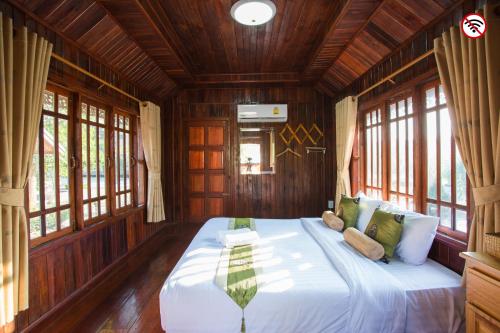 a bedroom with a large bed with wooden walls and windows at Grandsiri Resort KhaoYai in Mu Si