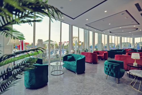 a lobby with chairs and tables and windows at Velipoja Grand Europa Resort, Affiliated by Meliá in Velipojë