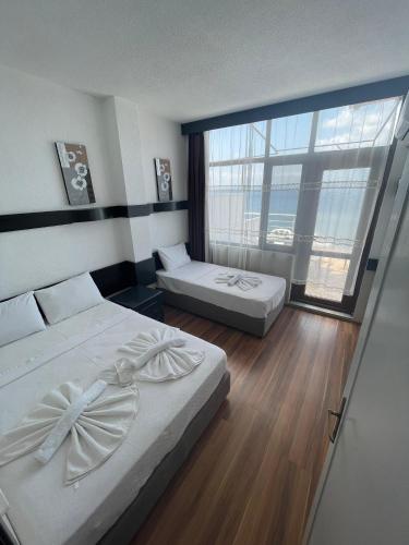 a hotel room with two beds and a large window at Alevok Hotel in Erdek