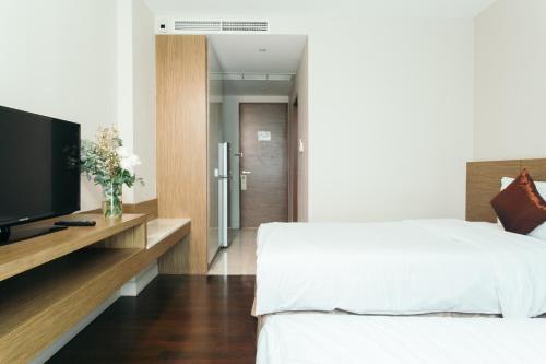 a bedroom with a bed and a flat screen tv at Thomson Residence Hotel in Bangkok