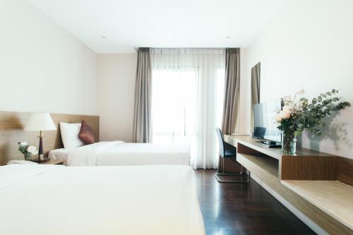 a hotel room with two beds and a television at Thomson Residence Hotel in Bangkok