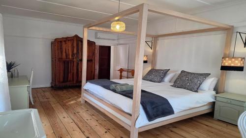 a bedroom with a canopy bed with a wooden floor at Paul René Manor House in Robertson