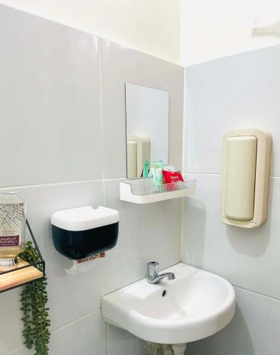 a white bathroom with a sink and a mirror at Sta Cruz Laguna Transient House in Santa Cruz