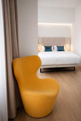a yellow chair in a bedroom with a bed at Aparthotel František in Světlá nad Sázavou
