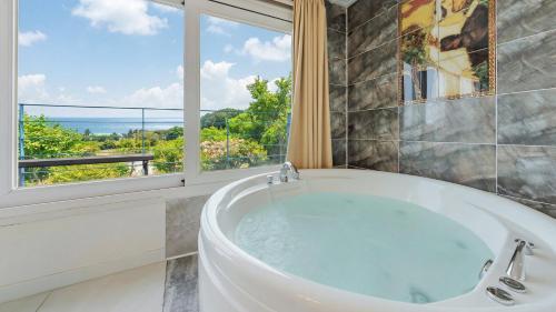 a bath tub in a bathroom with a window at Yangyang Monti Pet Spa Pension in Yangyang