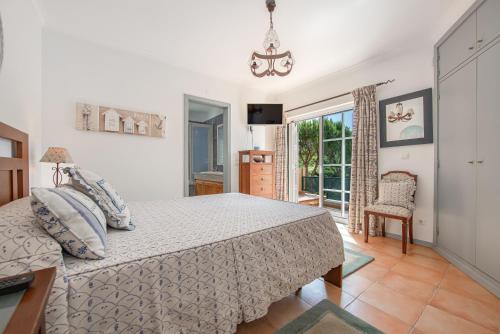 a bedroom with a bed and a chair and a window at Villa Praia Verde - Beach & Nature in Praia Verde
