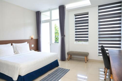 a bedroom with a bed and a table and windows at Lucky Hotel in Phước Lai
