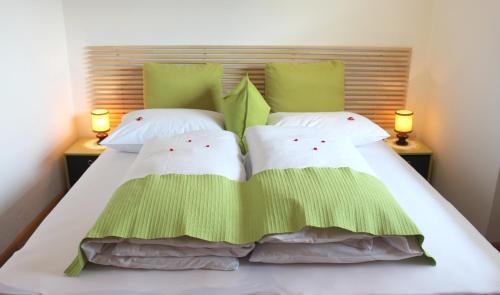uma cama com almofadas verdes e brancas e 2 candeeiros em Villa Malus em Castelbello