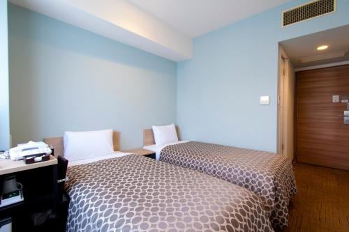 a hotel room with two beds and a desk at Community & Spa Naha Central Hotel in Naha