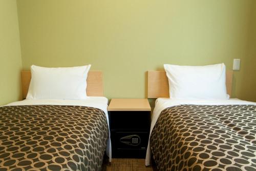 two beds sitting next to each other in a room at Community & Spa Naha Central Hotel in Naha