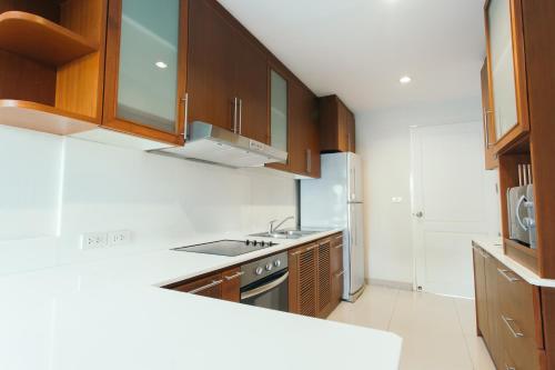 a kitchen with wooden cabinets and a sink and a stove at Thomson Residence Hotel in Bangkok