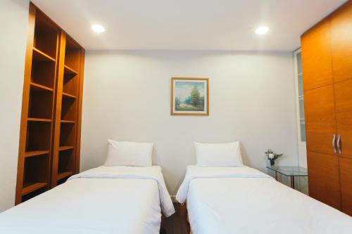 a room with three beds and a picture on the wall at Thomson Residence Hotel in Bangkok