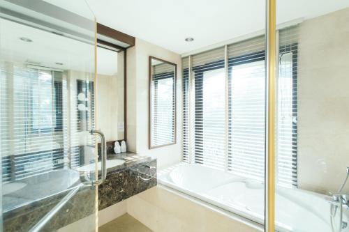 a bathroom with a tub and a sink and a shower at Thomson Residence Hotel in Bangkok