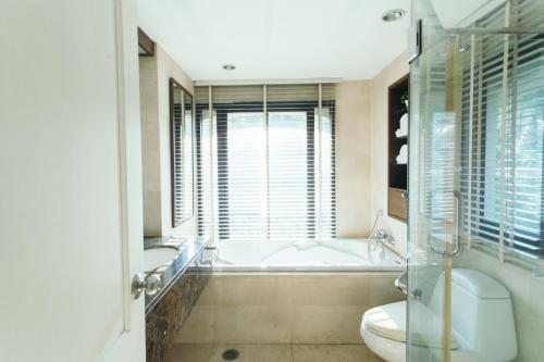 a bathroom with a tub and a toilet and a sink at Thomson Residence Hotel in Bangkok