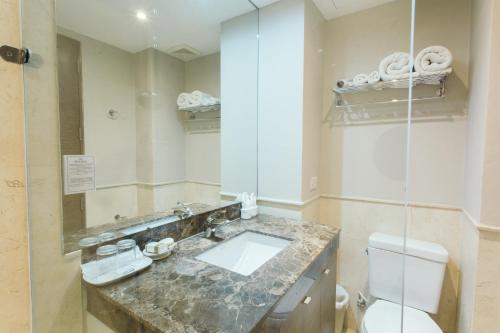 a bathroom with a sink and a toilet and a mirror at Thomson Residence Hotel in Bangkok