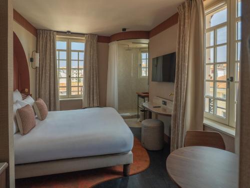 a hotel room with a bed and a television at Maison Atalaye - Hôtel entièrement rénové in Biarritz