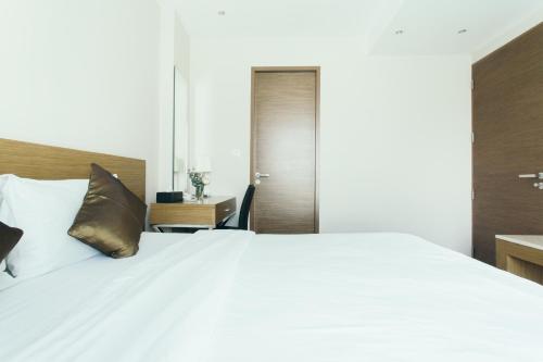 a bedroom with a large white bed and a desk at Thomson Residence Hotel in Bangkok