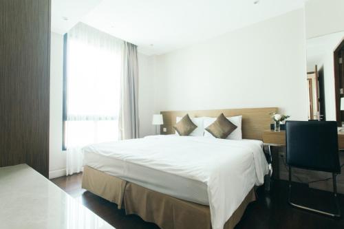 a bedroom with a large white bed and a window at Thomson Residence Hotel in Bangkok