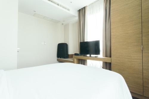 a bedroom with a bed and a tv and a window at Thomson Residence Hotel in Bangkok