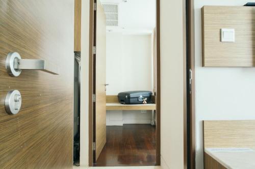 a door leading into a room with a desk with a suitcase at Thomson Residence Hotel in Bangkok