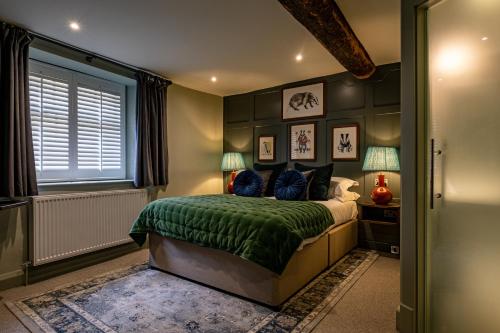 a bedroom with a bed with a green blanket at The Bell & Stuart House in Stow on the Wold