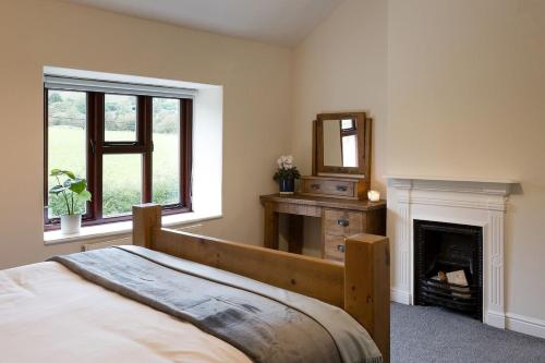 a bedroom with a bed and a mirror and a fireplace at Vera's cottage in Edale