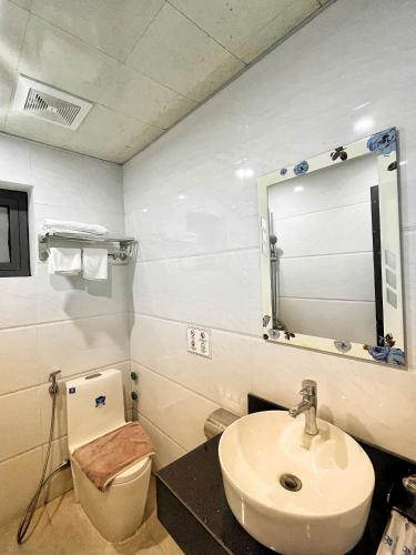 a bathroom with a sink and a toilet and a mirror at White Crown Hotel Ha Long in Ha Long