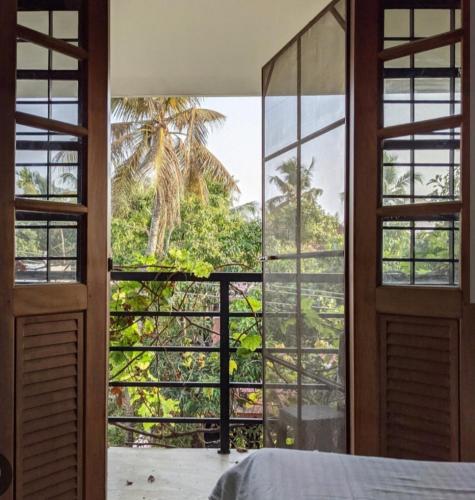 a bedroom with a window view of a palm tree at Goodkarma Inn in Cochin