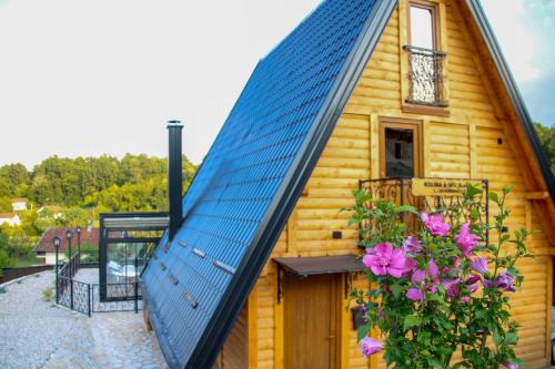 a blue roof on a wooden house with flowers at Koliba & SPA SlaDjo in Brčko