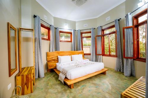 a bedroom with a bed and some windows at Chui hidden Lodge Karatu in Karatu