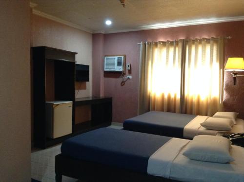 a hotel room with two beds and a television at Miami Inn in Cagayan de Oro