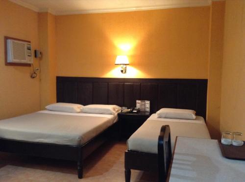 um quarto com duas camas e uma mesa com um candeeiro em Miami Inn em Cagayan de Oro