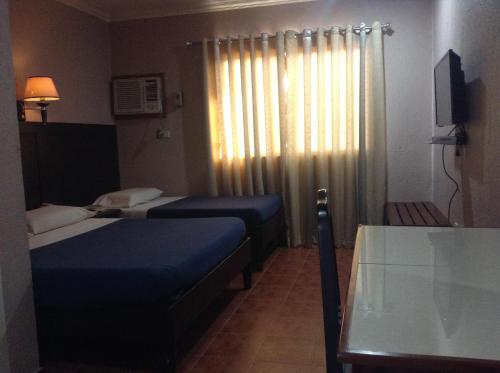 a room with two beds and a table and a window at Miami Inn in Cagayan de Oro