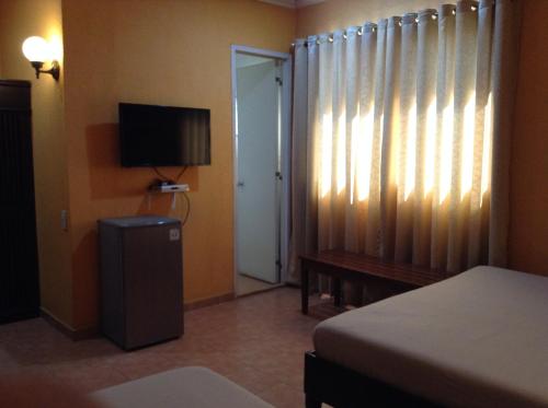 um quarto com uma cama, uma televisão e uma janela em Miami Inn em Cagayan de Oro