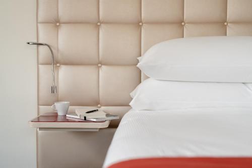 a bed with a side table with a cup and a book at Hotel St.Gotthard in Zurich