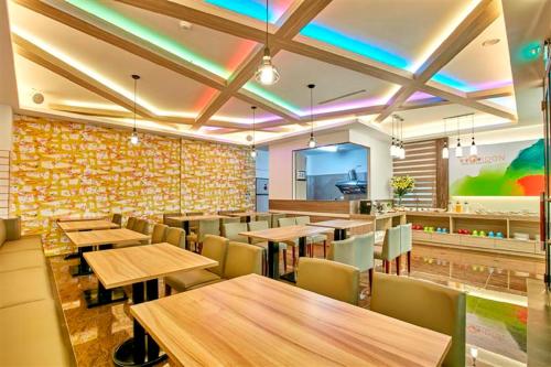ein Restaurant mit Holztischen und -stühlen und einer farbenfrohen Wand in der Unterkunft Gold Motel in Puxin