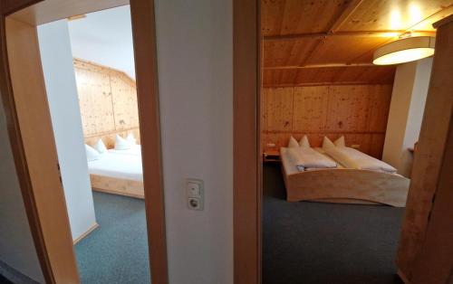 a room with two beds and a mirror at Gästehaus WOLFGARTEN in Sankt Jakob in Defereggen