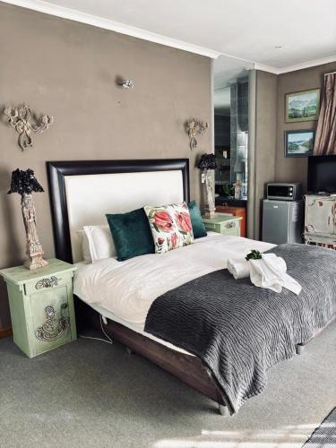 a bedroom with a large bed and a kitchen at La Grace Guestrooms in Kroonstad