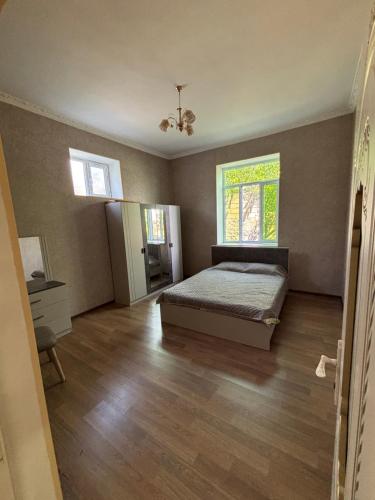 an empty bedroom with a bed and a window at Gunluk ev in Sheki