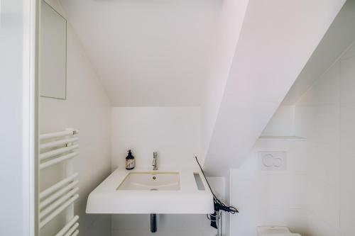 une salle de bains blanche avec un lavabo et des toilettes dans l'établissement ROMY BRUGES Historic Centre, à Bruges