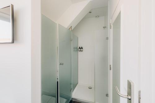 une douche en verre dans une salle de bains aux murs blancs dans l'établissement ROMY BRUGES Historic Centre, à Bruges