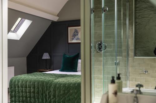 a bedroom with a green bed and a shower at The Bell & Stuart House in Stow on the Wold