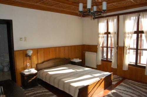 a bedroom with a large bed and two windows at Trevnenski Kat Hotel in Tryavna