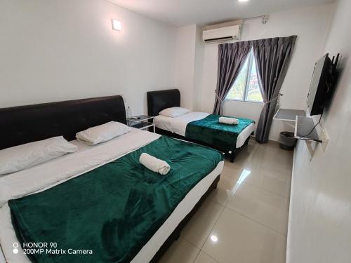 a hotel room with two beds and a window at Arkid 10 Guesthouse in Ipoh