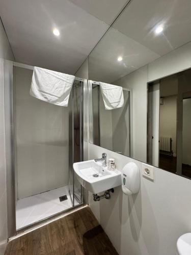 a bathroom with a sink and a shower and a mirror at IRUÑA ROOMs in Pamplona