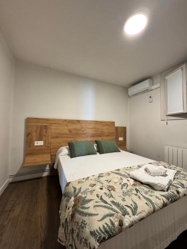 a bedroom with a large bed with a wooden headboard at IRUÑA ROOMs in Pamplona