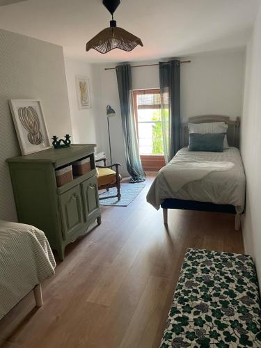 a bedroom with two beds and a table and a window at Le cottage à la glycine - Maison de charme au cœur des gorges de la Loire in Chambles