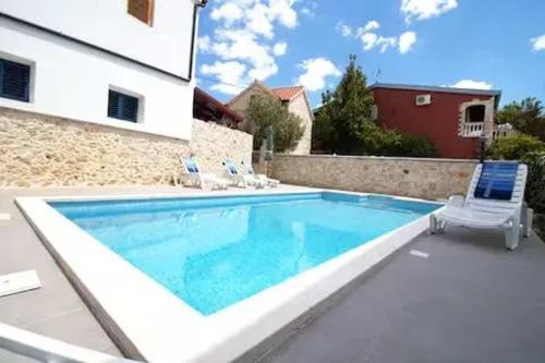 a swimming pool with two chairs and a house at Charming Villa in Jezera with Private Pool in Jezera